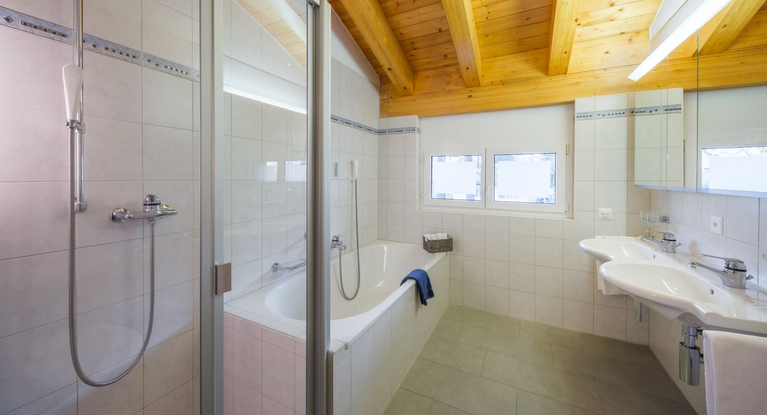 ABA Sporting 11: Badezimmer im Obergeschoss mit Badewanne, Dusche und zwei Lavabos.
